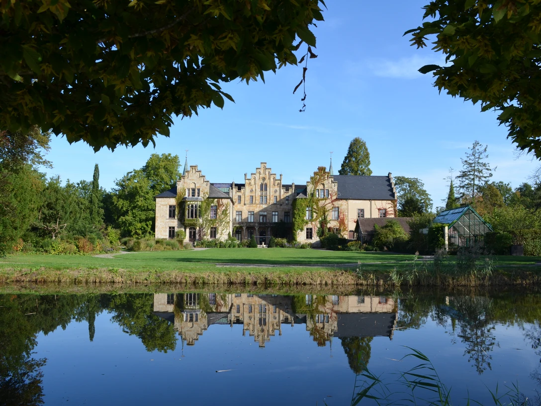Außenansicht Schloss Ippenburg Historisches Herrenhaus spiegelt sich idyllisch in einem Teich, umgeben von üppigem Grün.Historic manor house idyllically reflected in a pond surrounded by lush greenery.Historisk herregård, der idyllisk spejler sig i en dam omgivet af frodigt grønt.Historisch landhuis idyllisch weerspiegeld in een vijver omringd door weelderig groen.