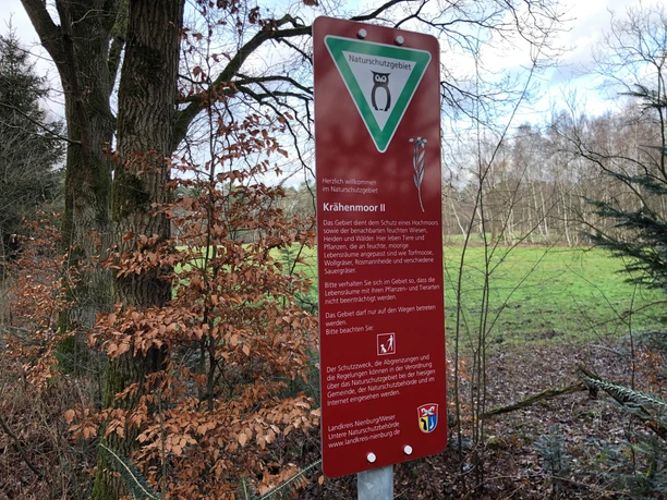 Krähentour Ein rotes Schild am Wegesrand informiert über das Krähennmoor, eine geschützte Naturfläche.