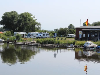 Campingplatz Drakenburg Ruhige Flussuferlandschaft mit Wohnmobilen und Bootsanlegestelle auf Campingplatz in Drakenburg.