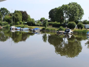 Ein ruhiger Campingplatz am Wasser mit Booten und grüner Umgebung, eingebettet in eine natürliche Landschaft.