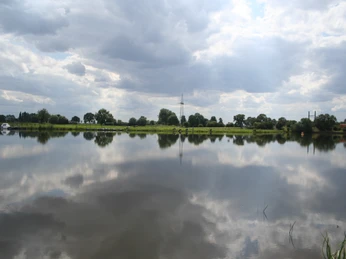 Blick auf eine ruhige Flusslandschaft der Weser bei Intscheder Wehr, Spiegelung der Wolken im Wasser.