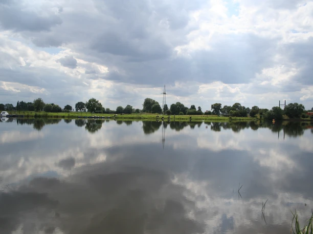 Blick auf eine ruhige Flusslandschaft der Weser bei Intscheder Wehr, Spiegelung der Wolken im Wasser.