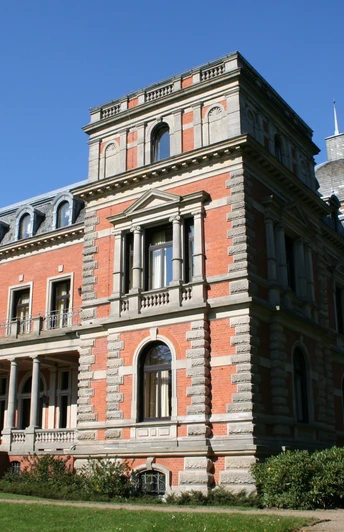 Das Bild zeigt das majestätische Schloss Etelsen in rotem Backstein mit prächtigen Verzierungen unter blauem Himmel.