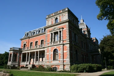 Schloß Etelsen Das Bild zeigt das majestätische Schloss Etelsen in rotem Backstein mit prächtigen Verzierungen unter blauem Himmel.