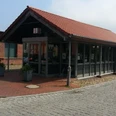 Bakstenen gebouw van één verdieping met rode bakstenen, glazen gevel en informatiebord aan de straat.