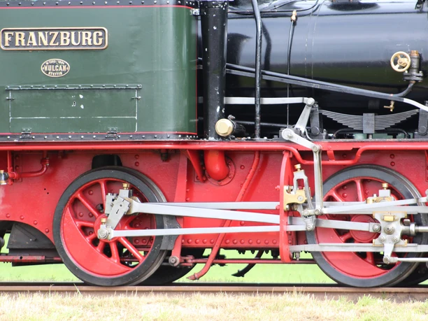 Historische stoomlocomotief met gedetailleerd mechaniek en rode wielen op het spoor in Bruchhausen-Vilsen.