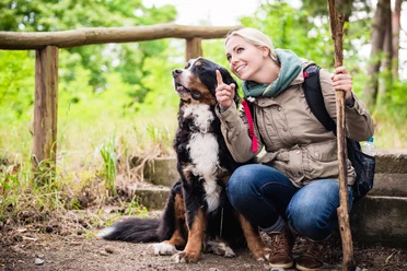 Mit Hund unterwegs, Foto:© Kzenon – stock.adobe Hiking woman with rucksack and her bernese mountain dog on a trail