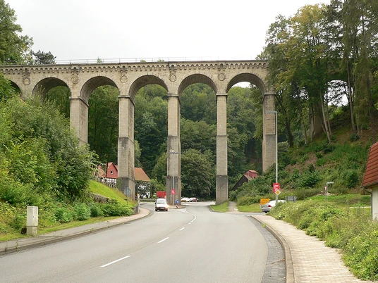 greener-viadukt Ein alter Viadukt mit großen Bögen, der über eine Straße verläuft.