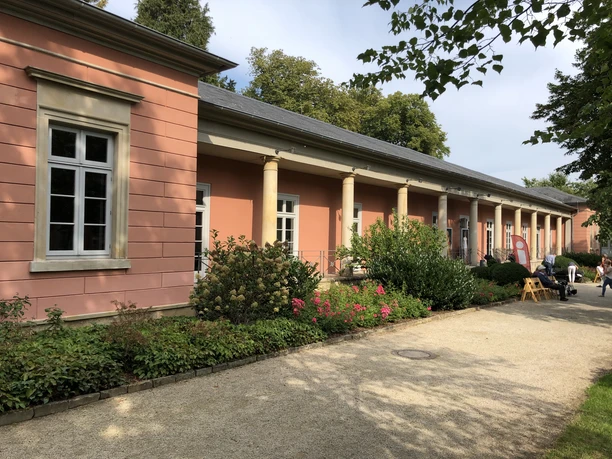 Roze gekleurd gebouw in Bad Rehburg, omringd door een goed onderhouden tuin en blauwe lucht op de achtergrond.