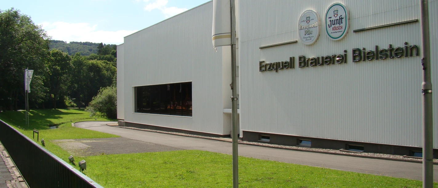Erzquellbrauerei Außenansicht der Erzquell Brauerei in Bielstein, mit großem Schriftzug und sonniger Umgebung.