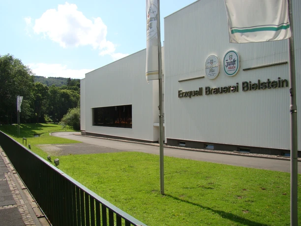 Erzquellbrauerei Außenansicht der Erzquell Brauerei in Bielstein, mit großem Schriftzug und sonniger Umgebung.