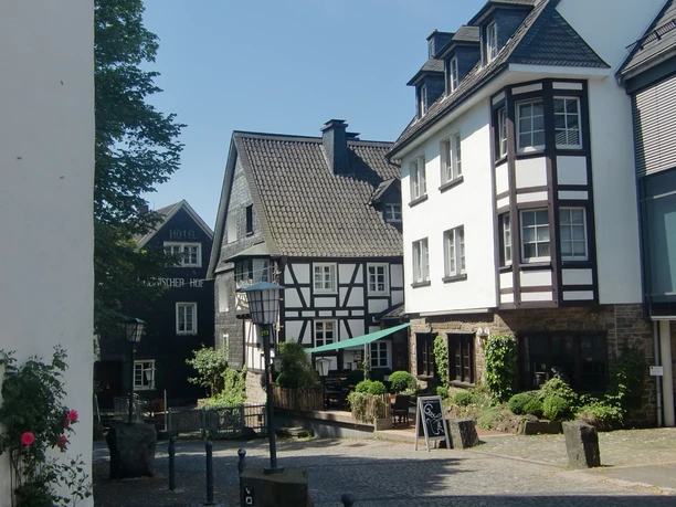 Ortskern Nümbrecht Fachwerkhäuser und ein Hotel in einer malerischen, sonnigen Gasse in Nümbrecht.