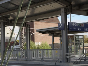 Modernisierter Bahnhof Lage Moderner Bahnhof mit überdachten Bahnsteigen, Glasfassaden und klarer Beschilderung.