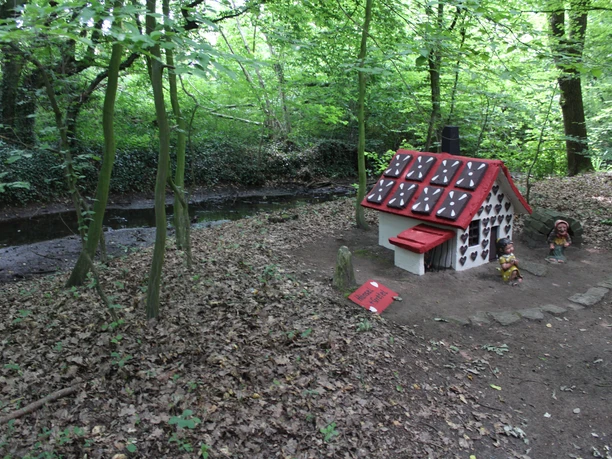 In het bos van Steyerberg staat een klein heksenhuisje met een rood en wit dak, omringd door weelderig groen.