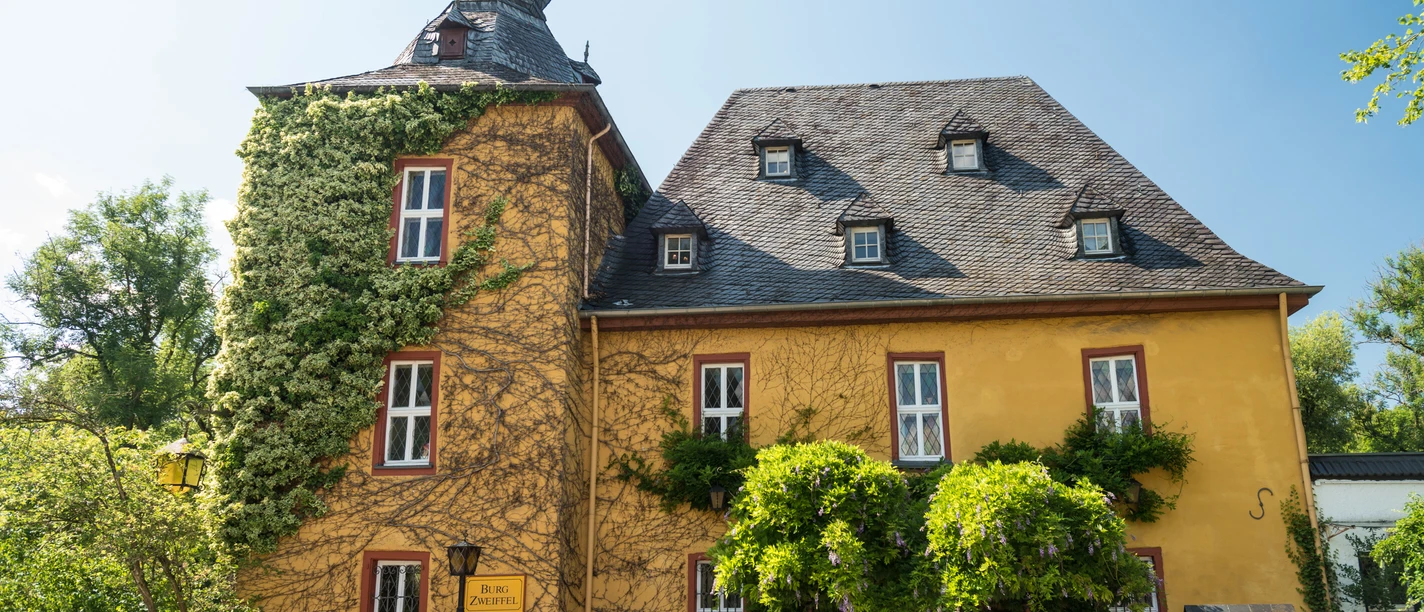 Burg Zweiffel <p>Schloss Bensberg in Bergisch Gladbach, ein barockes Gebäude mit einem markanten Turm und Kletterpflanzen.</p>