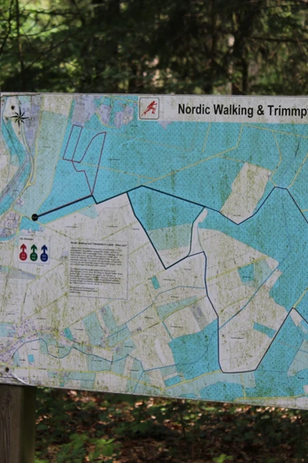 Wegweiser in einem Wald zeigt die Route des Nordic Walking und Trimpfads in Leese mit Startpunkten.