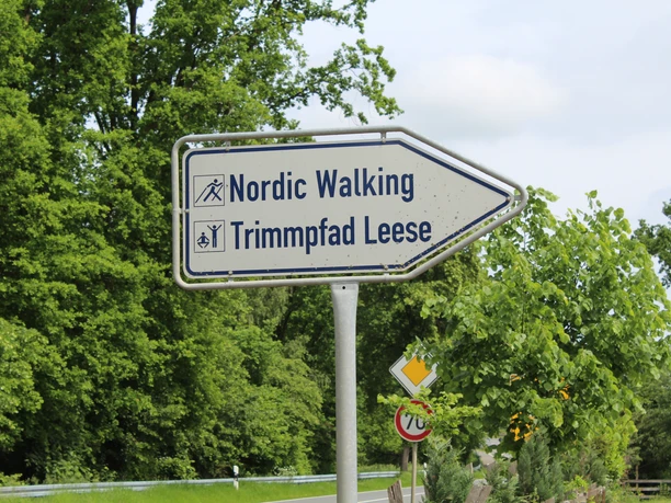 Nordic Walking und Trimpfad Leese Wegweiser in grüner Umgebung mit Hinweis auf Nordic Walking und Trimpfad Leese, verbunden mit Symbolen.