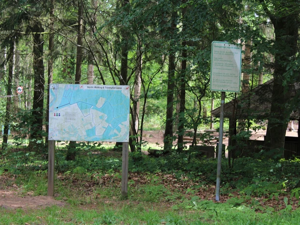 Een informatiebord en een bord in een bos markeren het begin van de Leese Nordic Walking en Fitness trail.