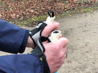 Nordic Walking Ein Nordic-Walking-Enthusiast hält, mit ihrer dunkelblauen Jacke bekleidet, fest die Stöcke.