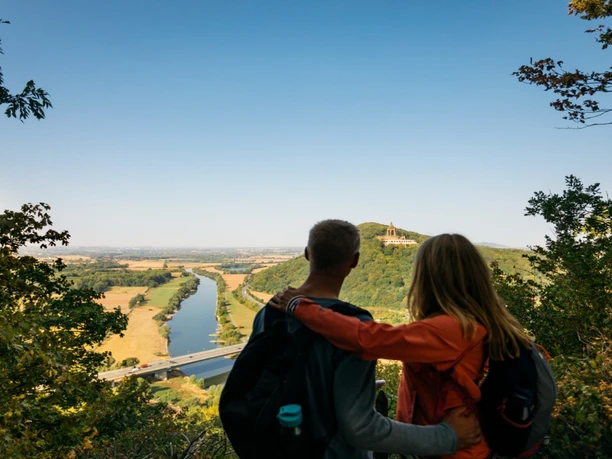 Ausblick Porta Kanzel Zwei Personen bestaunen den weiten Ausblick der bewaldeten Porta Kanzel über das Wesertal.