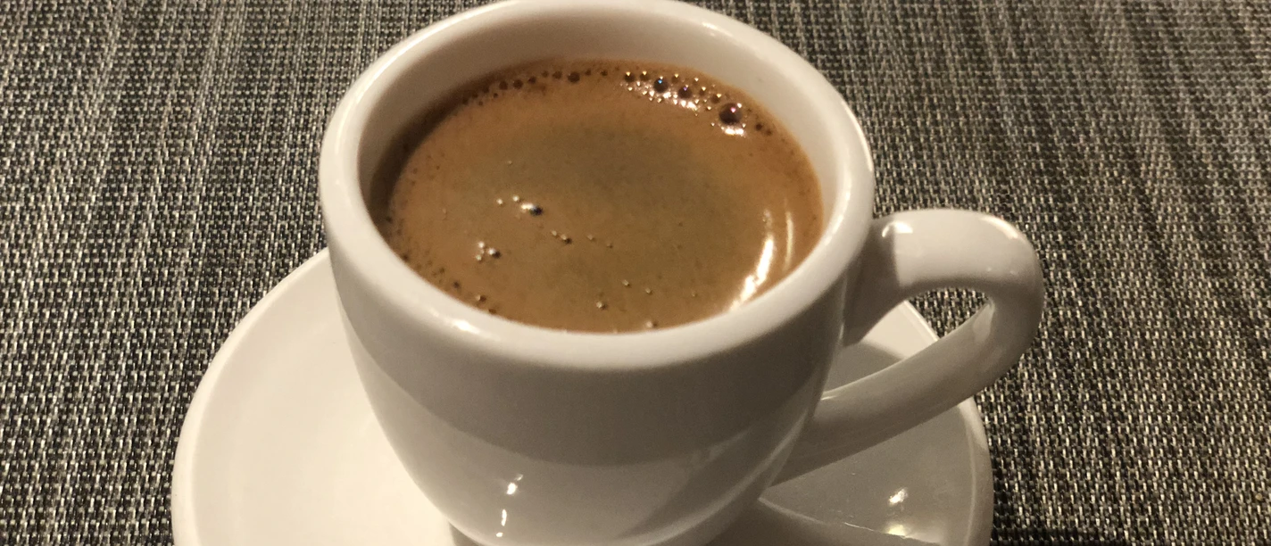 Espresso Eine weiße Espressotasse mit heißem, cremigem Espresso auf einem passenden Unterteller auf Stoffmatte.