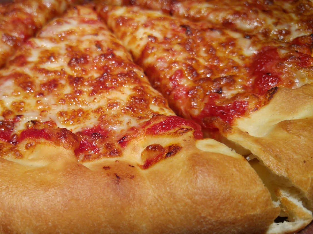 Pizza Eine perfekte, goldbraun gebackene Pizza mit geschmolzenem Käse und saftigem Tomatenbelag.