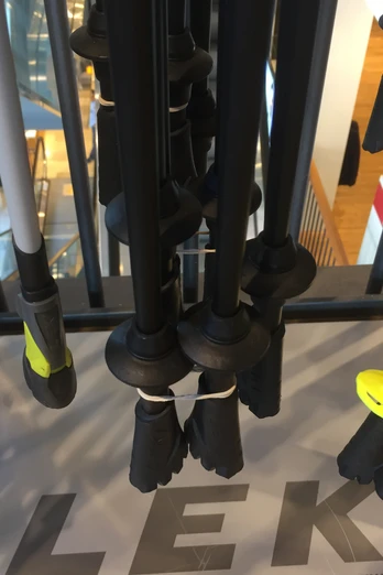 Nordic Walking-Stöcke unterschiedlicher Farben und Modelle hängen in einem Geschäft auf einem Ständer.