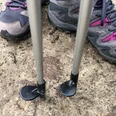 Wanderschuhe und Nordic Walking-Stöcke auf einem Betonweg, bereit für Outdoor-Aktivitäten.