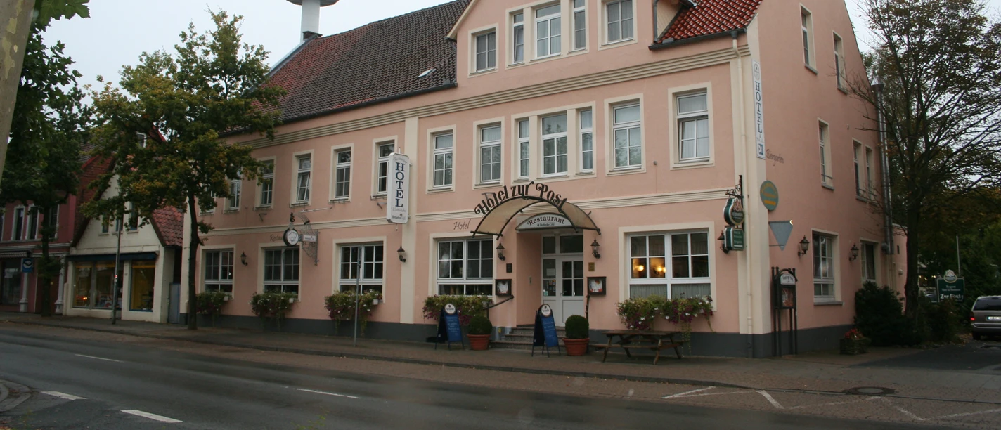 A pink-colored building with a traditional façade and several windows on two floors.