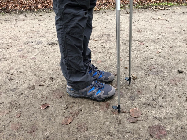 Nordic walking enthusiast in outdoor clothing on a nature trail with walking poles.