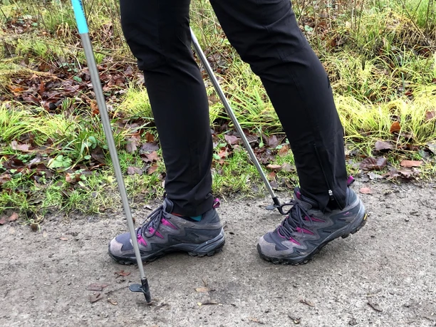 Nordic Walking Eine Person wandert in Outdoor-Bekleidung mit Nordic-Walking-Stöcken auf einem Naturweg.
