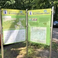 Terrainkurwege Bruchhausen-Vilsen Zwei Infotafeln in Bruchhausen-Vilsen mit Wanderkarten stehen auf einem befestigten Parkplatz im Grünen.