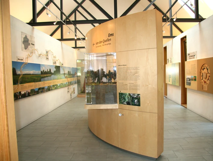 Moderne Ausstellung mit holzverkleideten Informationstafeln und Modellen zur Ems im Infozentrum.