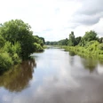 Große Aue bei Liebenau Fluss Große Aue windet sich durch üppige Landschaft nahe Liebenau unter bewölktem Himmel mit dichter Vegetation.