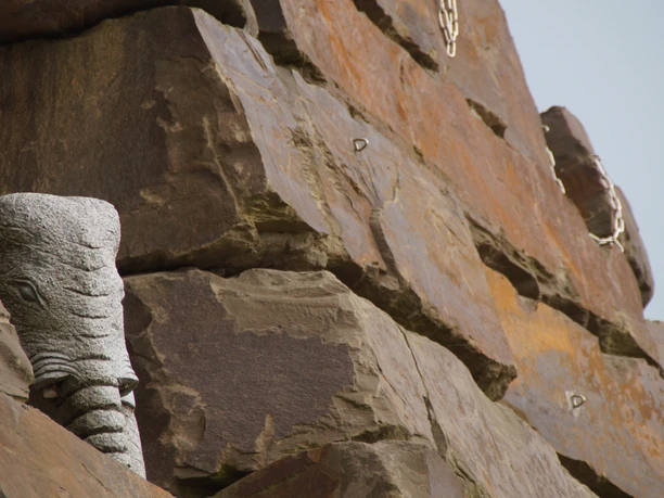 Steinbruch Lindlar Steinerne Elefantenskulptur ragt aus einer Mauer in Lindlar, eingerahmt von groben Felsblöcken.