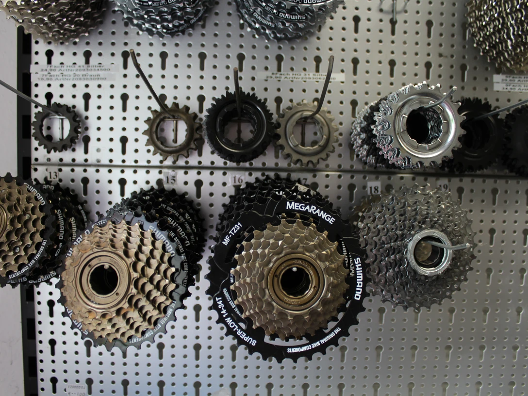 Fahrradreparatur Verschiedene Fahrradritzel und Kassetten hängen geordnet an einer perforierten Metallwand.