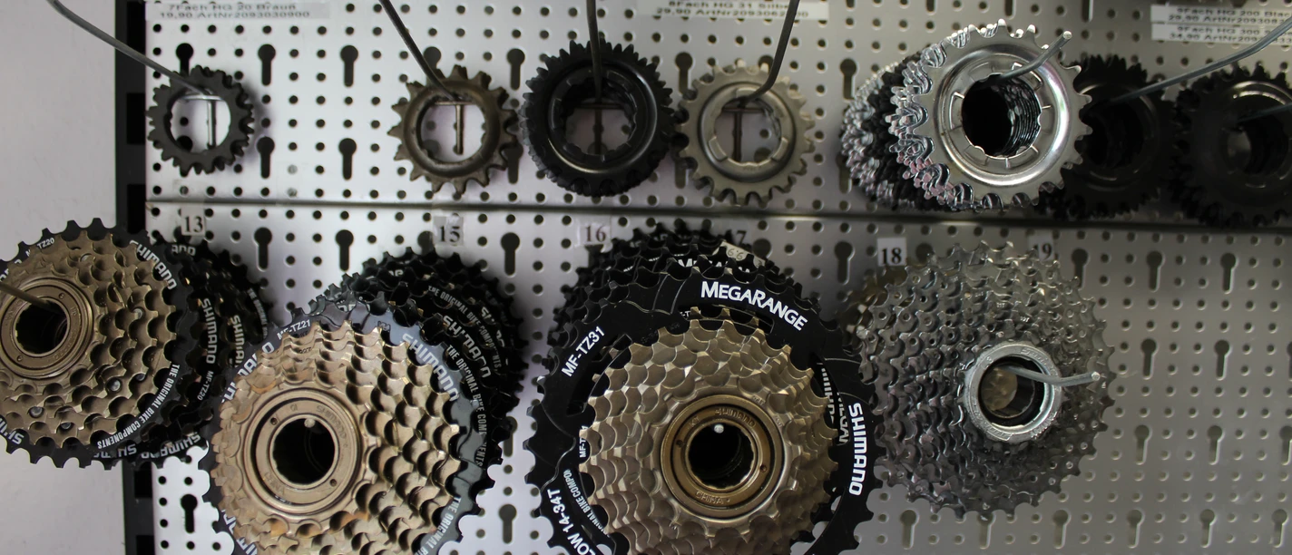 Fahrradreparatur Verschiedene Fahrradritzel und Kassetten hängen geordnet an einer perforierten Metallwand.