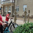 Familienskulptur Petershagen Zwei Radfahrer betrachten eine metallerne Skulpturengruppe in einer historischen Altstadt.