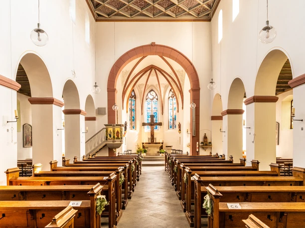 Innenstadt <p>Innenansicht einer Kirche mit Holzbänken und buntem Glasfenster im Hintergrund.</p>
