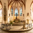 Innenstadt Der Chor einer Kirche mit Altar, bunten Glasfenstern und gotischen Gewölben.