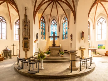 Innenstadt Der Chor einer Kirche mit Altar, bunten Glasfenstern und gotischen Gewölben.