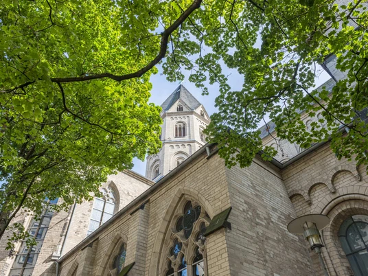 St. Andreas Romanische Kirche St. Andreas, harmonische Mischung aus Backsteinarchitektur und grünem Laub.Romanesque church of St. Andrew, harmonious blend of brick architecture and green foliage.