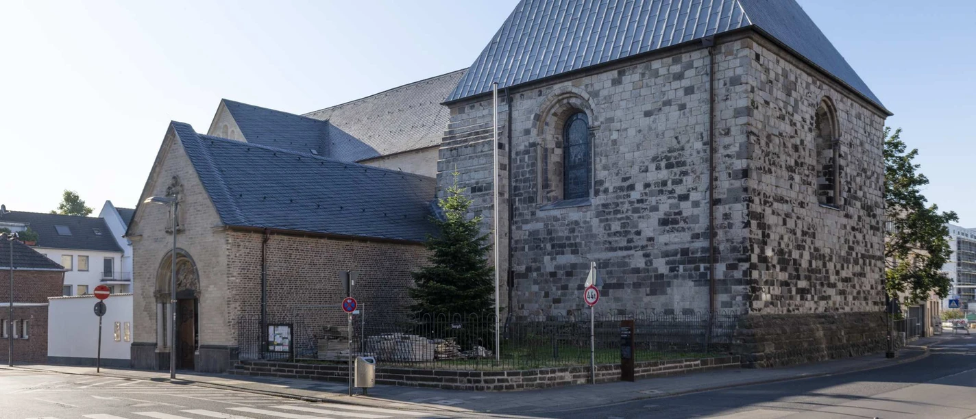 Sankt Georg Romanische Kirche St. Georg mit Natursteinfassade und steilem Satteldach bei Tageslicht.