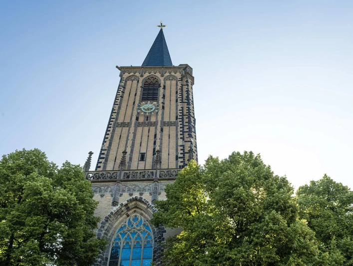 Saint Severin Historische Kirche Sankt Severin mit prächtigem Uhrturm, umgeben von grünen Baumkronen.Historic church of St. Severin with a magnificent clock tower, surrounded by green treetops.