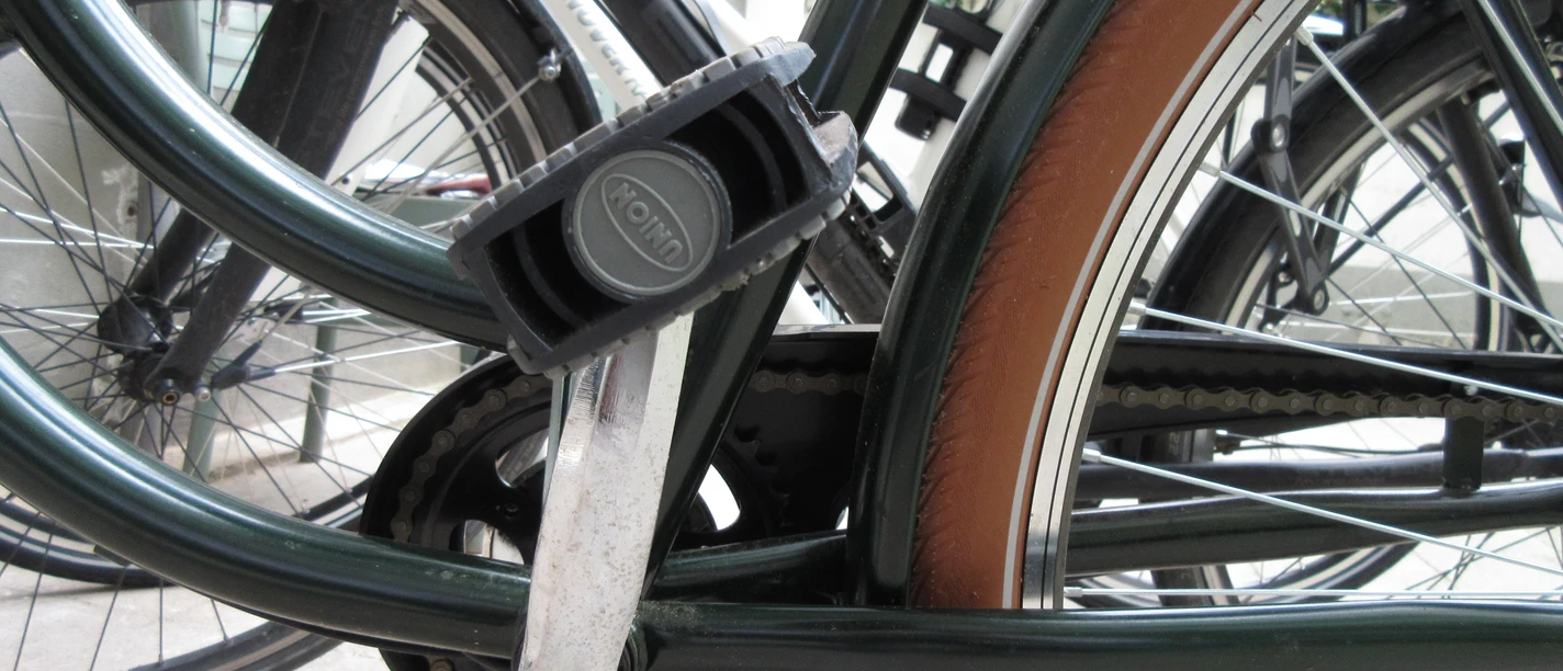 Rad Ein schwarzes Fahrrad steht auf einem Betonboden; ein Pedal und die Kettenlöcher sind im Fokus.