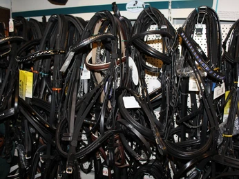 Reiterhof Wikner Lederne Zügel und Halfter hängen dicht aneinander in einem gut sortierten Reiterbedarfsgeschäft.