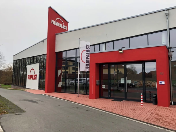 Filmpalast Nienburg, moderner Kinokomplex mit verglaster Fassade und markantem roten Eingangsschild.