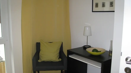 Ferienwohnung Hofen Ein gemütlicher Sessel in einer Ecke mit einem Beistelltisch, Lampe und dekorativer Schale.