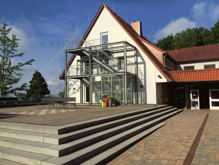 Jugendgästehaus Rödinghausen - Terrasse und Eingang Jugendgästehaus Rödinghausen mit breiter Eingangstreppe, Glasfassade und modernen Metallstrukturen.