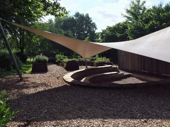 Jugendgästehaus Rödinghausen - Artrium mit Kräutergarten Kreisförmige Sitzstufen im Jugendgästehaus Rödinghausen. Hölzerne Pergola spendet Schatten.